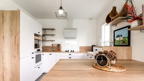 A modern kitchen with white cabinets, a wooden countertop, and a large window.