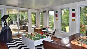A covered patio area with a stationary bike, a children's play area with toy trains, and a dining table with chairs.