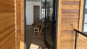A wooden interior with a glass door leading to a dining area with a bench and table.