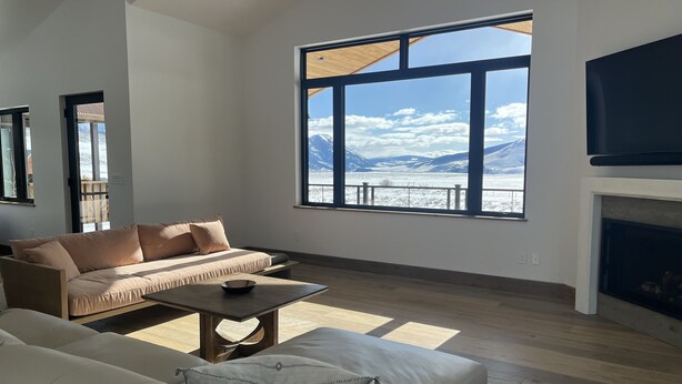 A spacious living room with a large window offering a mountain view, a fireplace, and a modern sofa.