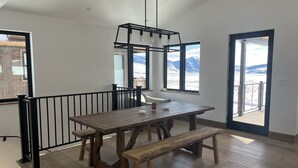 A spacious room with a large wooden dining table, benches, and a hanging light fixture.