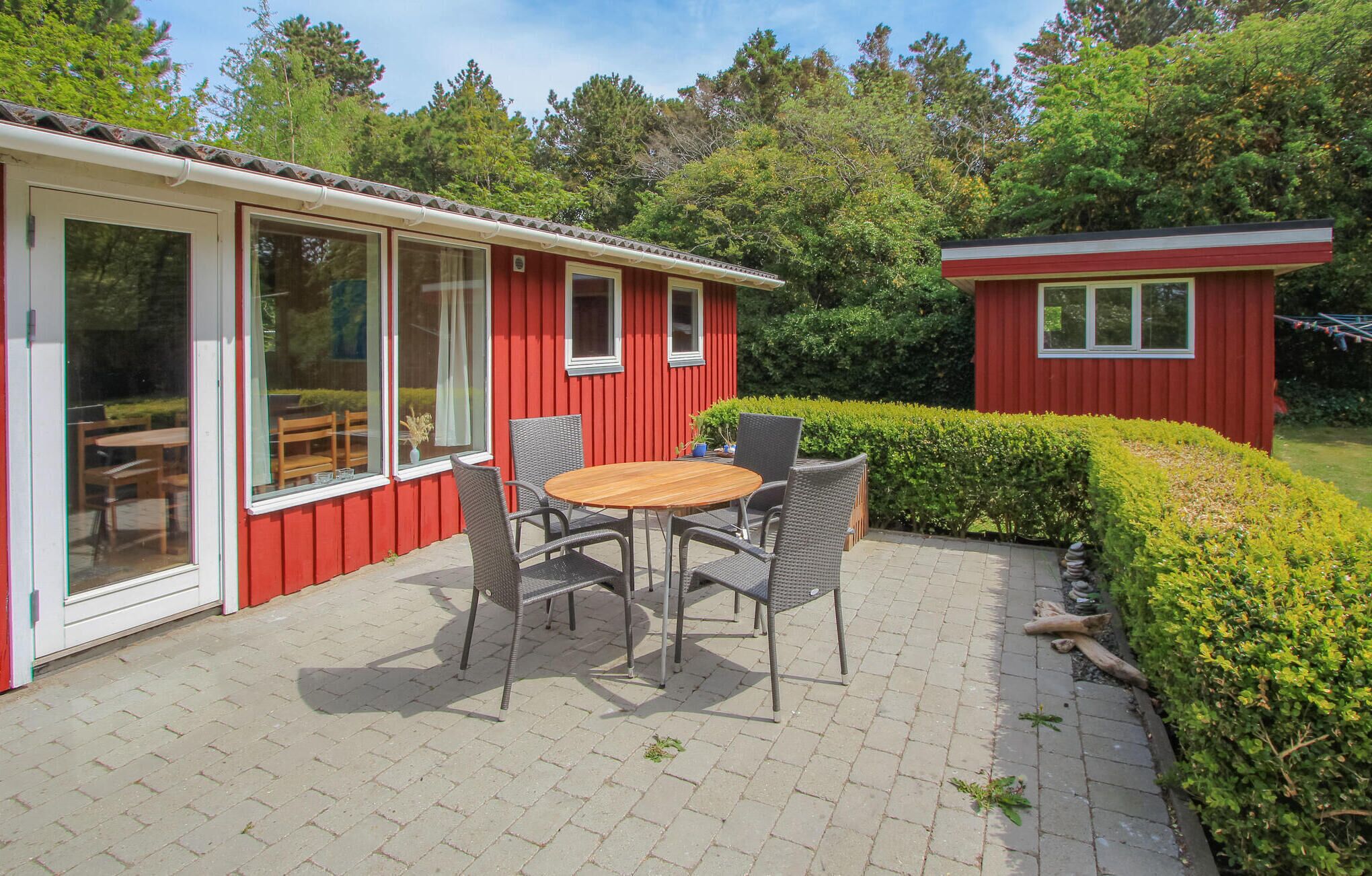 Een rood gebouw met grote ramen en een terras met een tafel en stoelen.