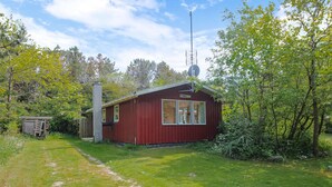 Pieni punainen mökki, jossa on savupiippu, ikkuna ja satelliittiantenni.