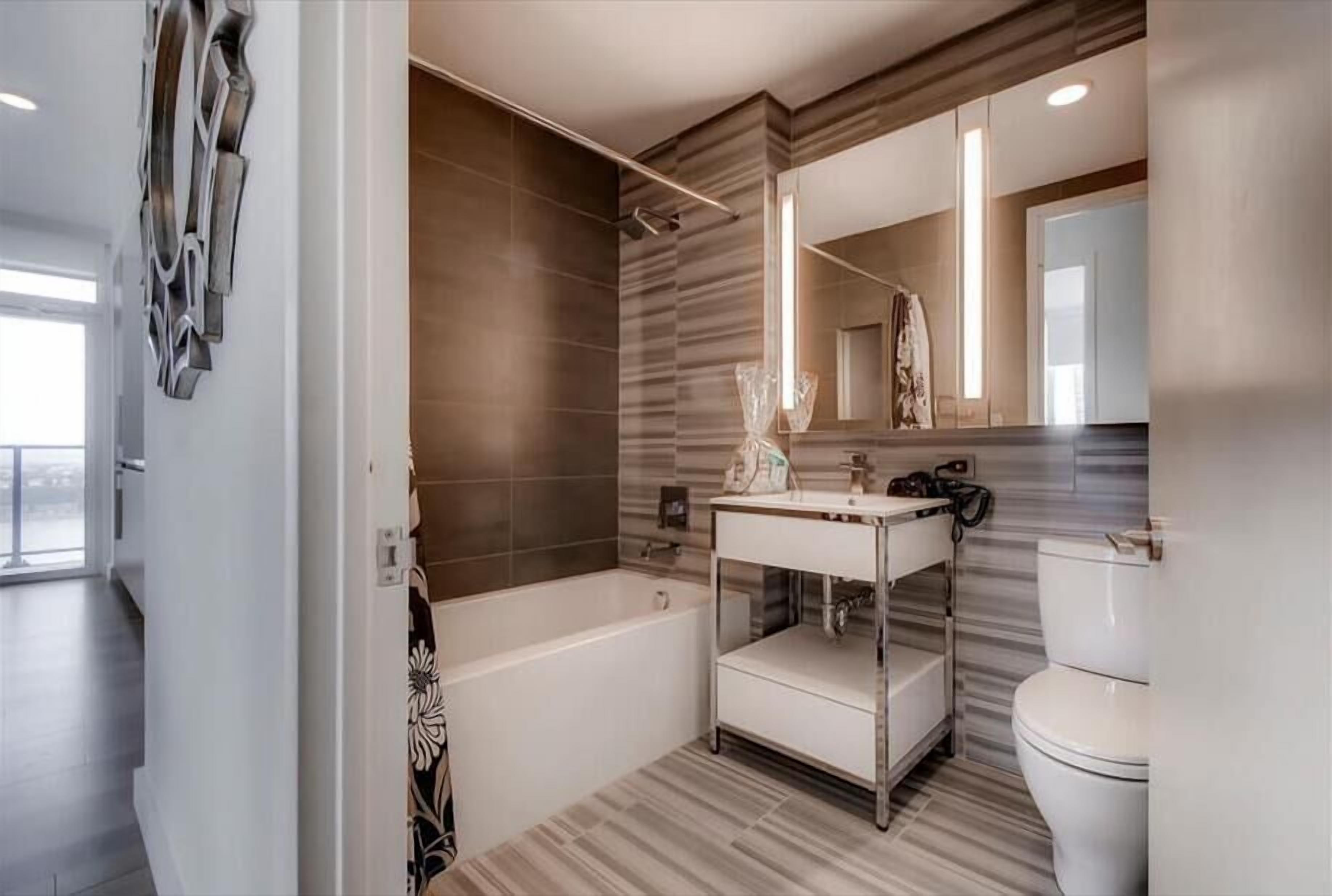 A modern bathroom with a freestanding bathtub, a vanity with a mirror, and a toilet.