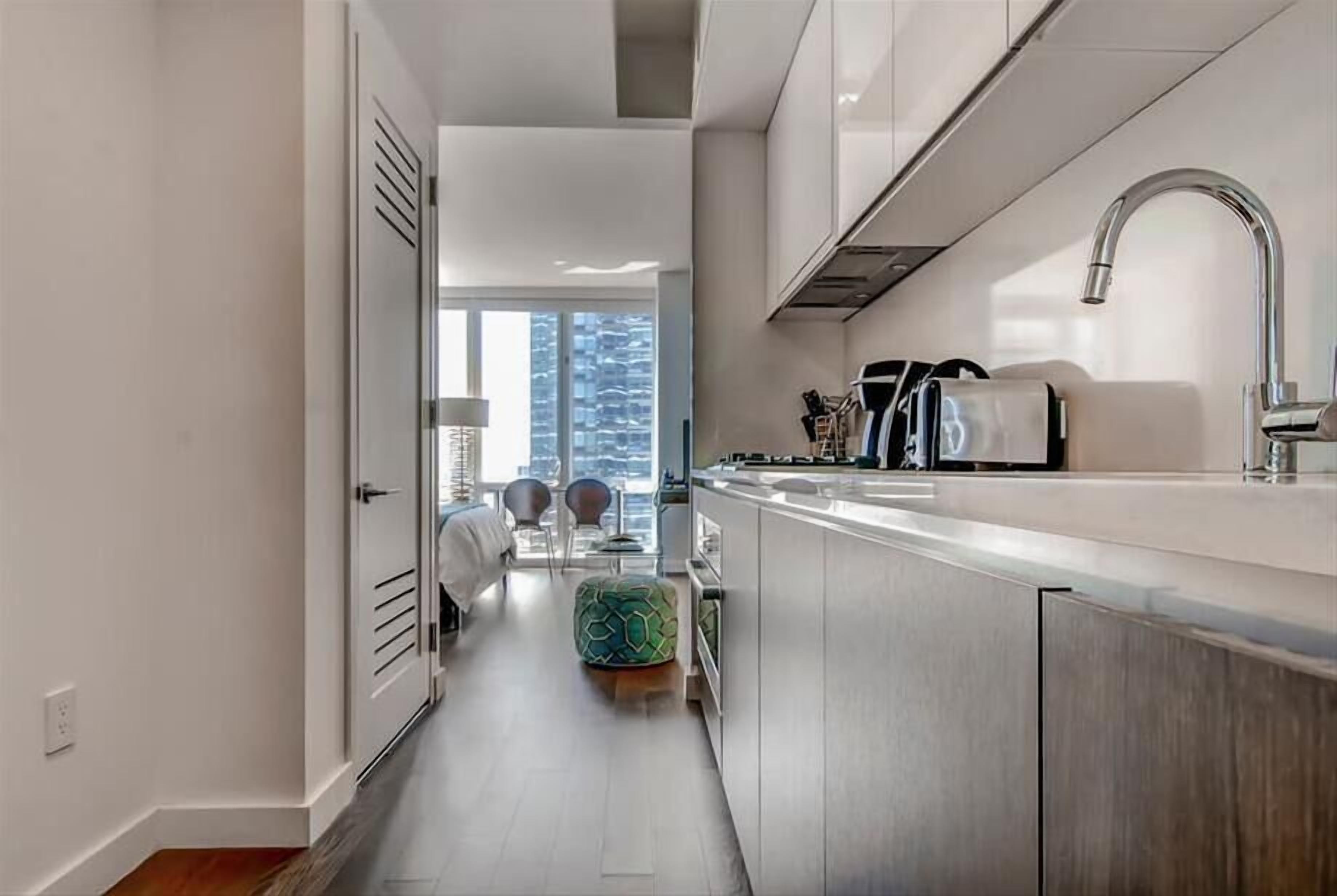 Una cucina moderna con lavello in acciaio inossidabile, forno integrato e finestra con vista sulla città.