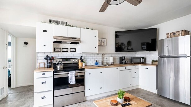 Eine moderne Küche mit weißen Schränken, Edelstahlgeräten und einem hölzernen Deckenventilator.