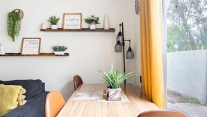 Ein moderner Essbereich mit Holztisch und braunen Stühlen, einem schwarzen Sofa und einem Fenster mit gelben Vorhängen.