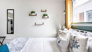 Ein Schlafzimmer mit einem Bett, einem Spiegel und Regalen an der Wand mit Pflanzen.