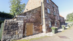 Un edificio de piedra con letrero que dice "The Old Mill", con una puerta de madera, ventanas y una chimenea.