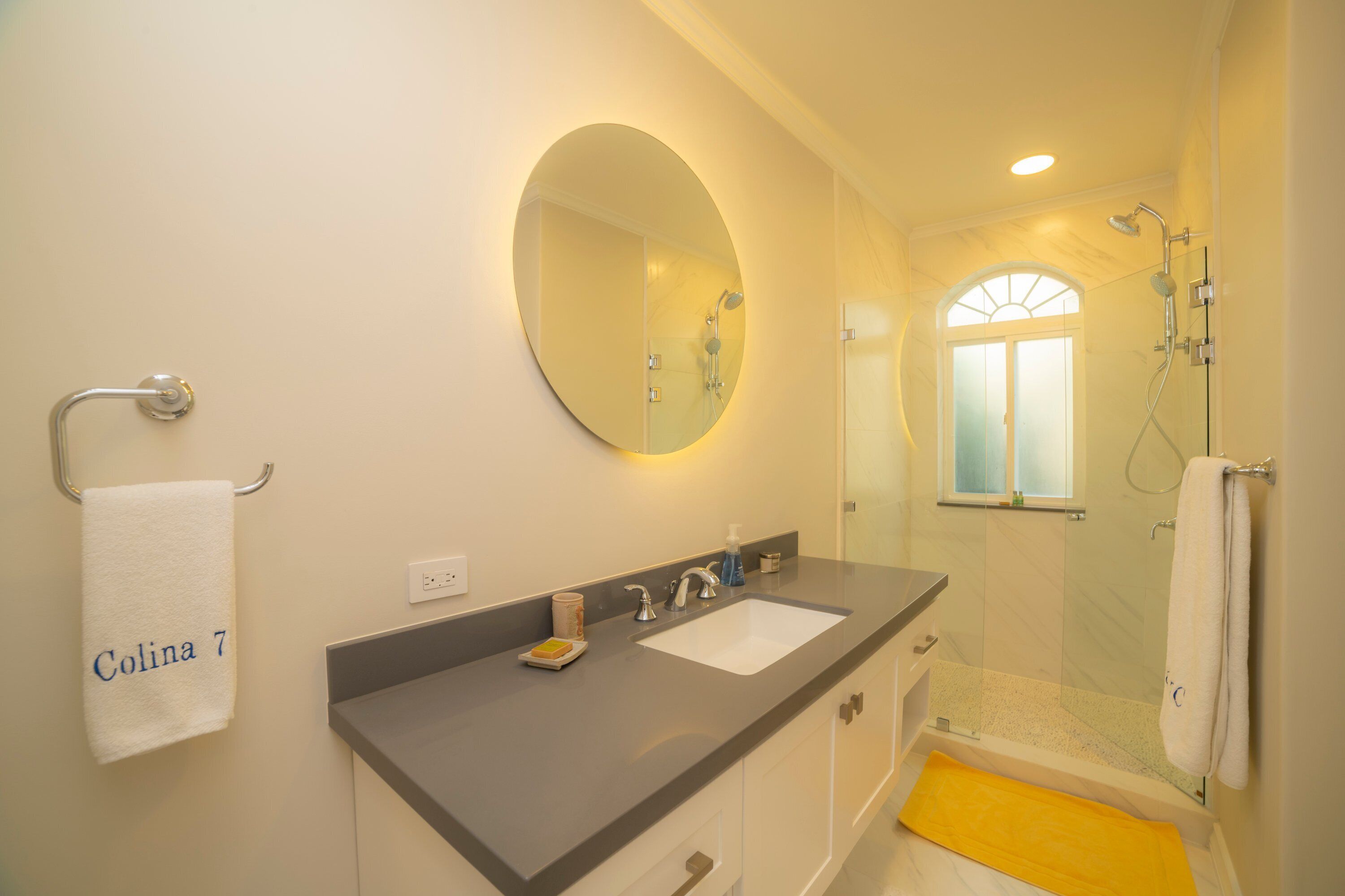 Ein Badezimmer mit Waschbecken, Spiegel und Dusche.