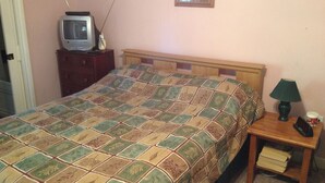 A bedroom with a bed, a wooden nightstand, a lamp, a framed picture on the wall, and a dresser. - Cabin in Bankhead National Forest (Moulton)
