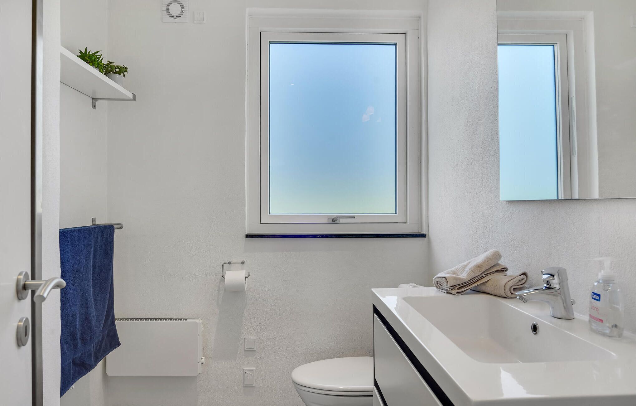 Een moderne badkamer met toilet, wastafel en raam.