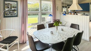 En matplats med ett runt bord, stolar, en vas med blommor och ett fönster med gardiner.