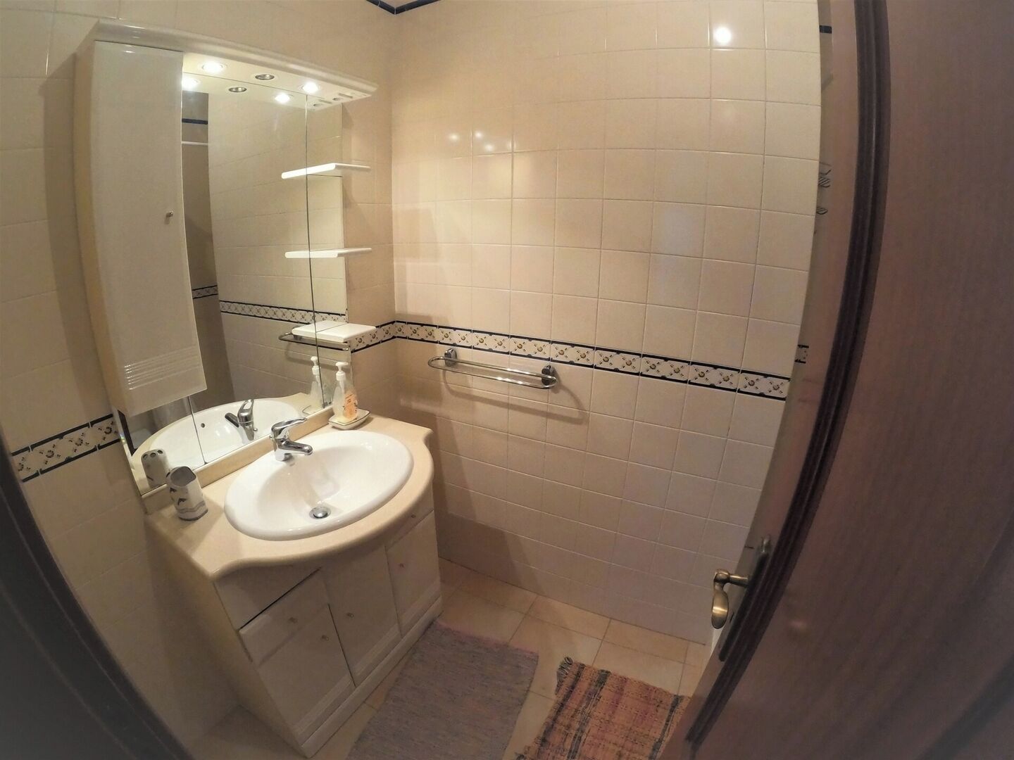 A bathroom with a sink, mirror, towel rack, and tiled walls.