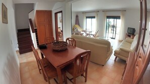 A dining area with a wooden table and chairs, a sofa, and a TV in a living room. - Algarve, 4 Bedrooms Independent House, Pêra (Pêra)