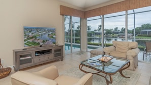 A living room with a television, a glass coffee table, and a sofa.