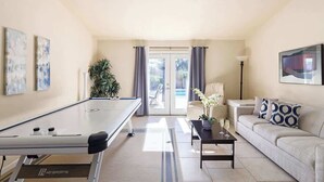 Una sala de estar con mesa de billar, sofá, mesa baja y planta.