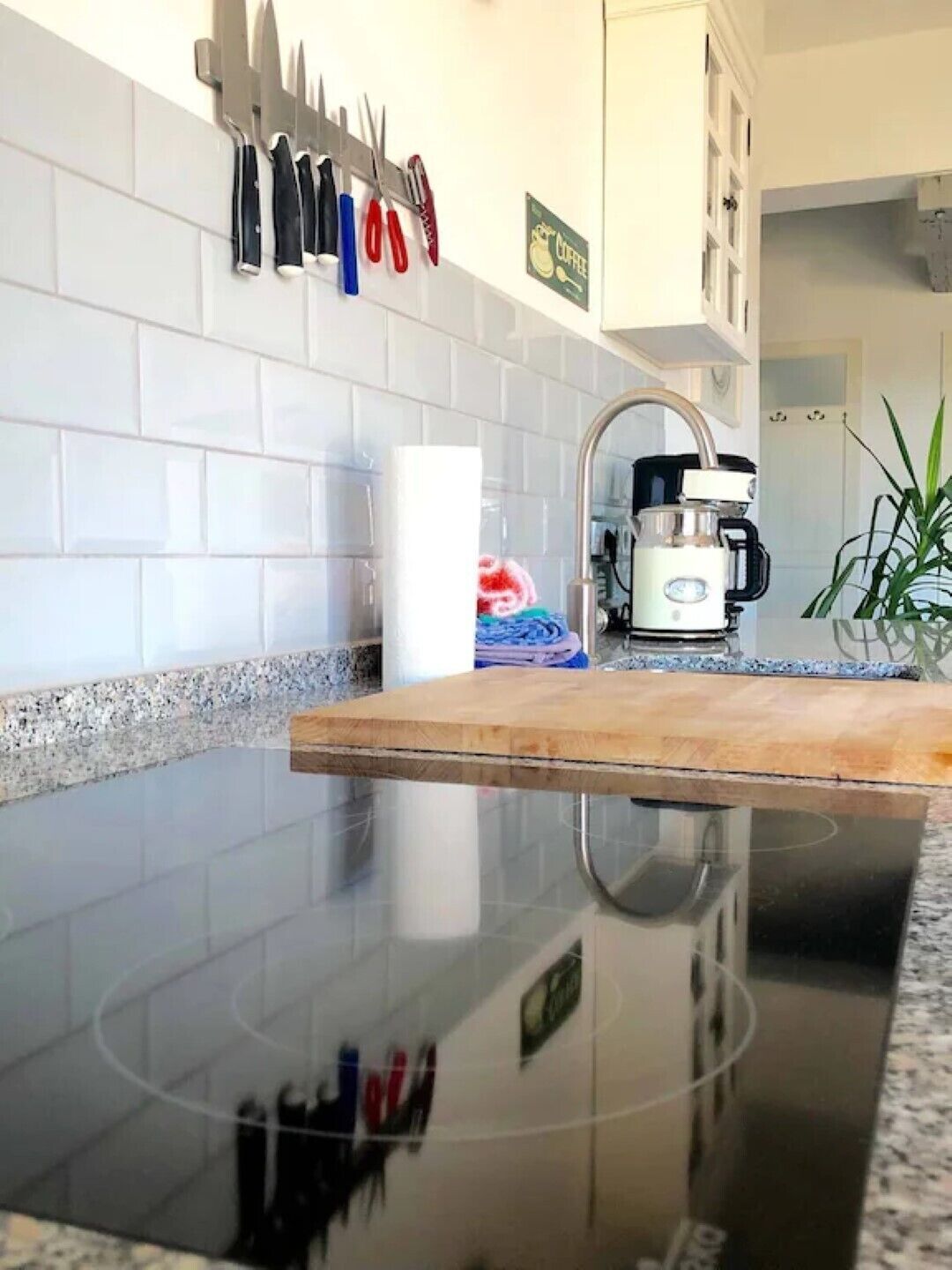 A kitchen with white tiles, a wooden countertop, and a coffee machine.