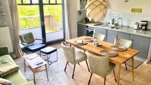 A modern kitchen with a wooden table and chairs, a coffee machine, and a view of the garden through the sliding glass door. - Vacation apartment "Belt" with two bedrooms - close to the beach - on the island of Fehmarn (Fehmarn)