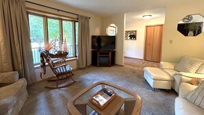 Ein Wohnzimmer mit Schaukelstuhl, Fernseher, Couchtisch und Sofa.