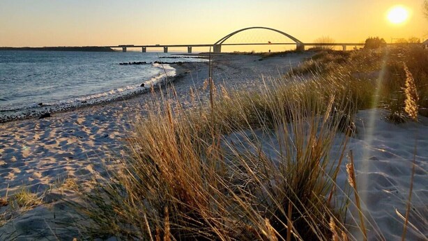 A beach with a bridge in the background.