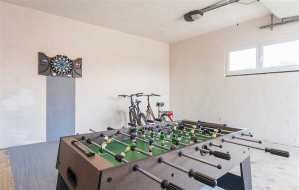 A room with a foosball table, dartboard, and bicycles.