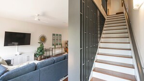 Ein Wohnzimmer mit Flachbildfernseher, einer Couch, einem Deckenventilator und Wanddekoration.