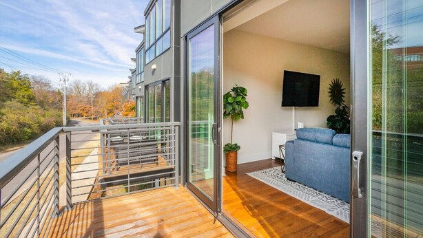 Eine moderne Wohnung mit Balkon, einer Couch, einem Fernseher und einem Blumentopf.