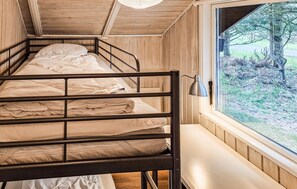 Un lit superposé avec une fenêtre, des murs en bois et une tête de lit en métal.