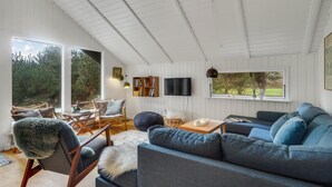 A cozy living room with a large window, a television, and a bookshelf.