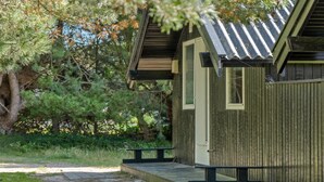 A small wooden cabin with a porch, a window, and a door.