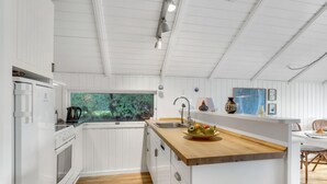 A modern kitchen with white cabinetry, a wooden countertop, a built-in sink, and a window overlooking greenery.