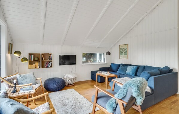 Un salon spacieux avec un plafond haut, un grand canapé bleu, une table basse en bois et une bibliothèque.