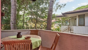 Un balcon avec une table et des chaises, donnant sur un immeuble avec un toit en tuiles et un escalier.