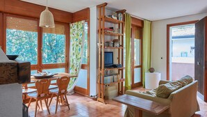 Une pièce chaleureuse avec une table à manger en bois, des chaises, une bibliothèque et un canapé.