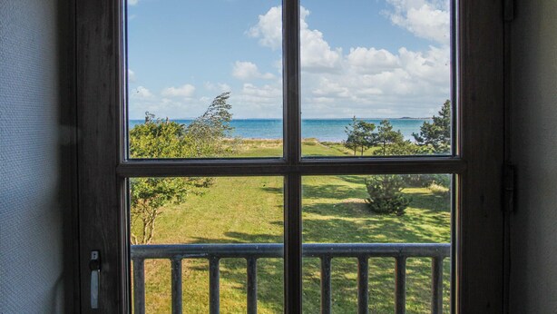 Una ventana con vista a un campo verde y el océano.