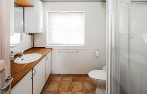 Une petite salle de bain avec un lavabo blanc, des toilettes et un espace douche.