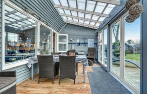 A covered patio with wicker furniture, a table, and a view of the outside. - Cozy home in Hadsund with WiFi (Hadsund)