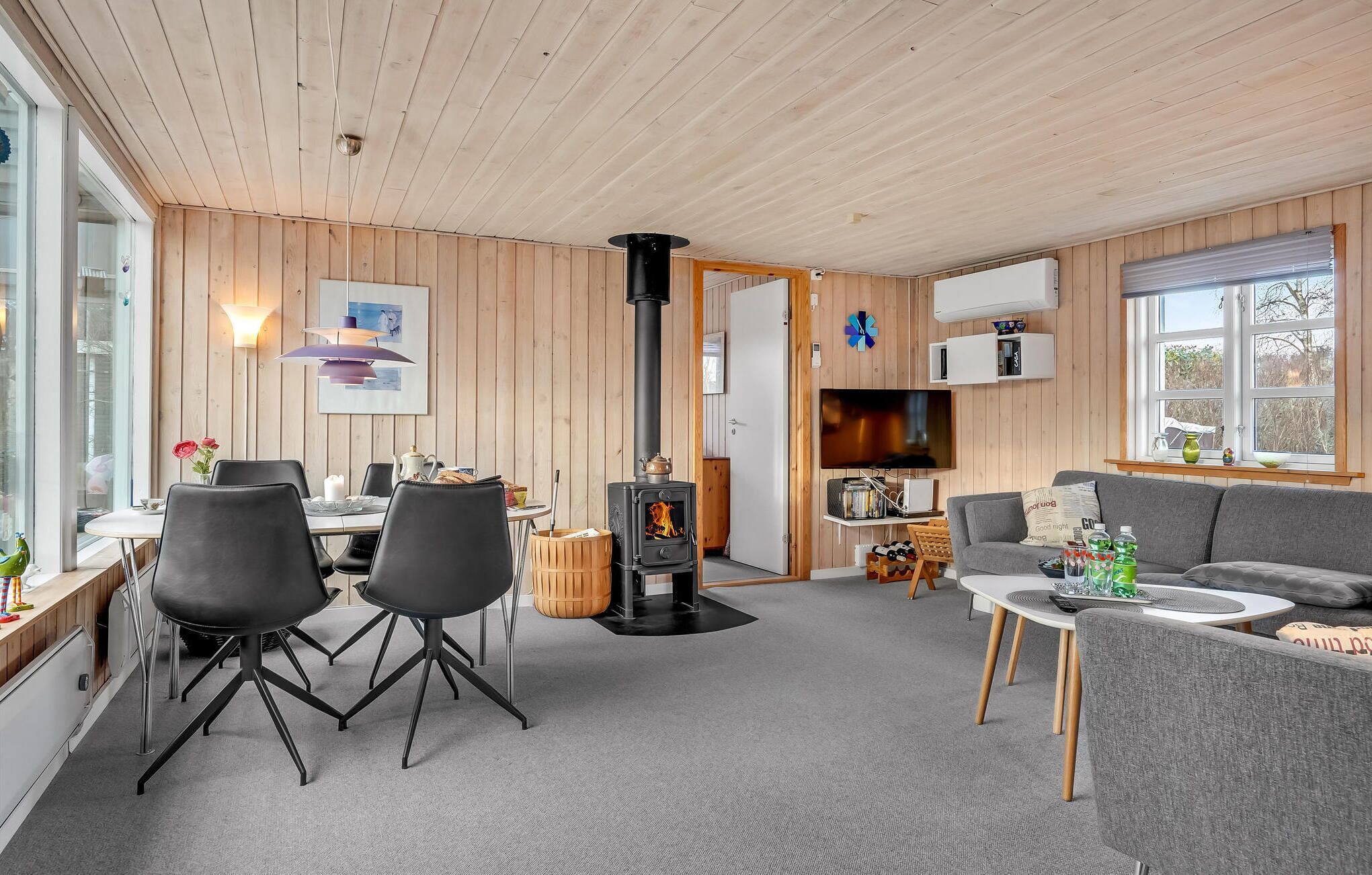 Ein modernes Wohnzimmer mit Kamin, Essbereich und einer Couch.