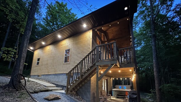 A two-story log cabin with a wooden deck and outdoor seating area. - Secluded 3 bedroom Log Cabin,Kid Friendly,In Logan Ohio,in Hocking Hills,Hot Tub (Logan)
