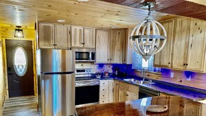 A modern kitchen with wooden cabinets, stainless steel appliances, and a central island. - Secluded 3 bedroom Log Cabin,Kid Friendly,In Logan Ohio,in Hocking Hills,Hot Tub (Logan)