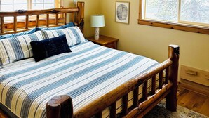 A bedroom with a wooden bed, a ceiling fan, and two windows with wooden frames. - Coveted location perfectly close to town, golf, lake & park with surplus parking (McCall)