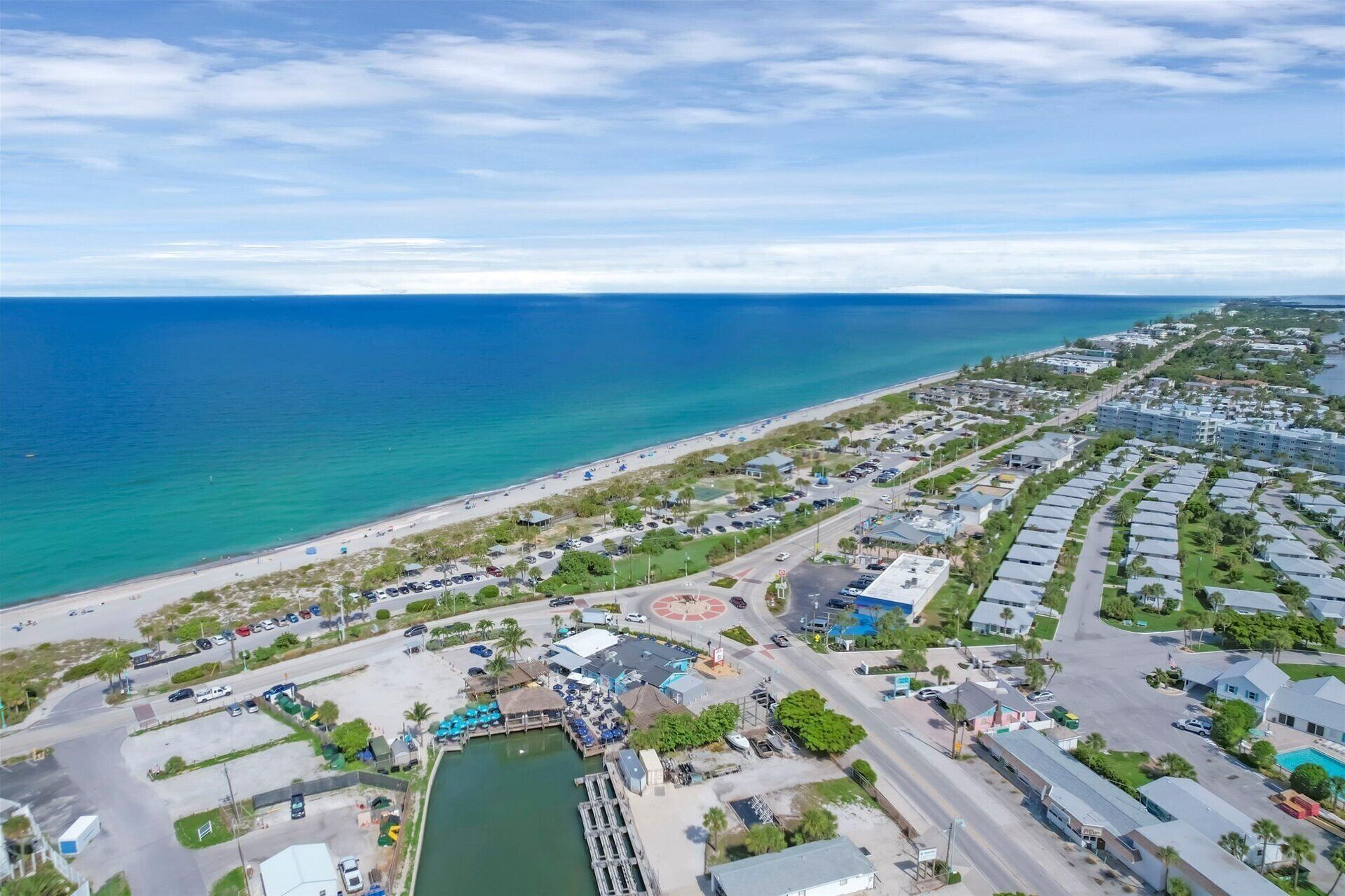 Vista aérea de um resort costeiro com marina, praia e edifícios residenciais.