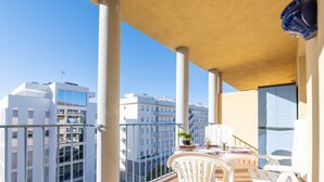 A balcony with white chairs and a table, overlooking a cityscape with modern buildings. - Beautiful apartment for 4 people with WIFI, pool, TV and terrace (Roses)