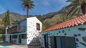 Una casa de dos pisos con fachada de piedra, piscina y vistas a las montañas.