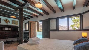 Un dormitorio con una cama, una silla, un escritorio y una ventana con vistas a la montaña.