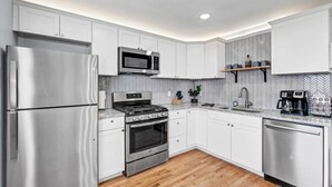 A modern kitchen with stainless steel appliances, white cabinetry, and a herringbone-patterned backsplash. - Bourbon House 4 - The Wellingmoor - Hot Tub (Louisville)