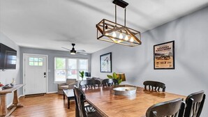 A spacious dining area with a wooden table and chairs, a hanging light fixture, and a framed poster on the wall. - Bourbon House 4 - The Wellingmoor - Hot Tub (Louisville)