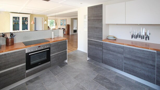 A modern kitchen with grey cabinetry, a built-in oven, and a wooden countertop. - Awesome home in Samsø with sauna (Samsø)