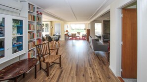 A spacious living area with a wooden floor, a bookshelf, a dining table with chairs, and a seating area with sofas and armchairs. - Awesome home in Samsø with sauna (Samsø)